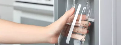 Abertura do post sobre como funciona o Purificador de Água: Mão enchendo copo em Purificador